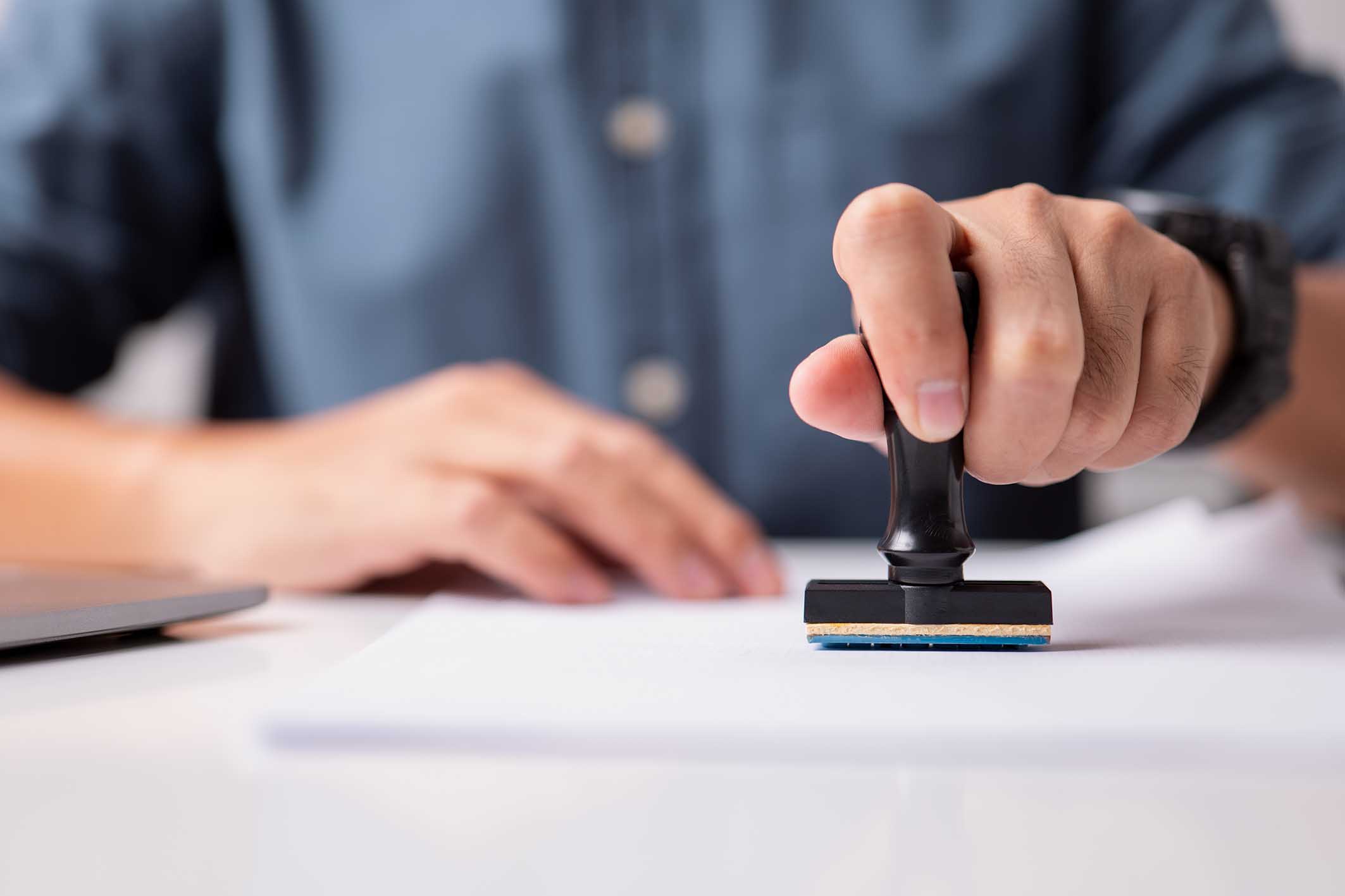 Close-up of a person's hand stamping on an approved application